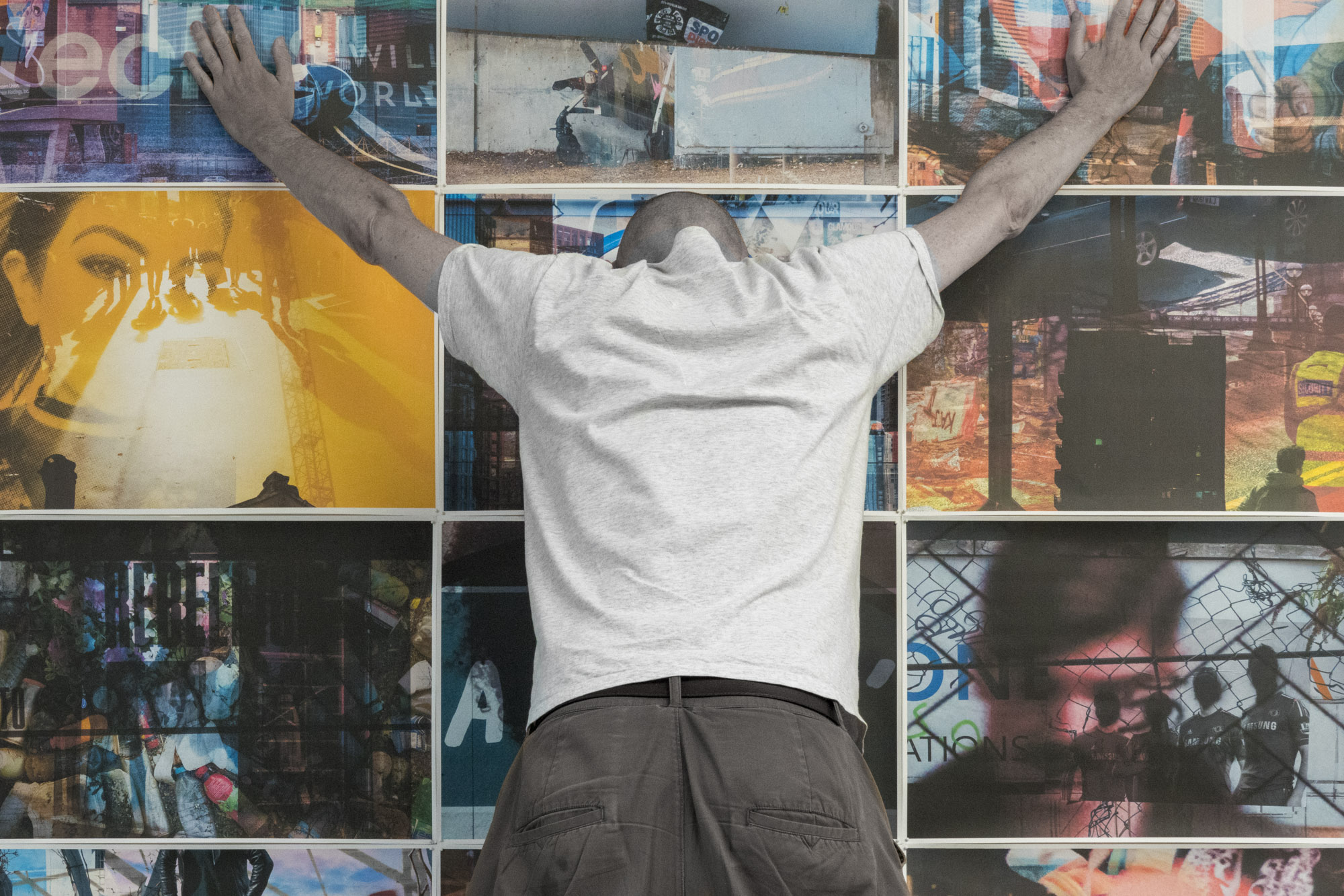 a figure wearing a Deliveroo jacket leans against a grid of collaged photographs