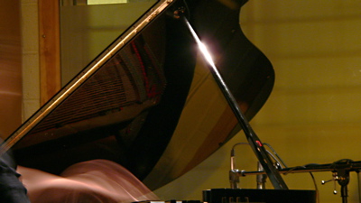 Image of piano lid, blurred hands playing