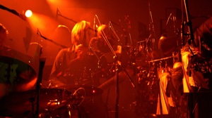 Image of Sakamoto playing with video screen behind him