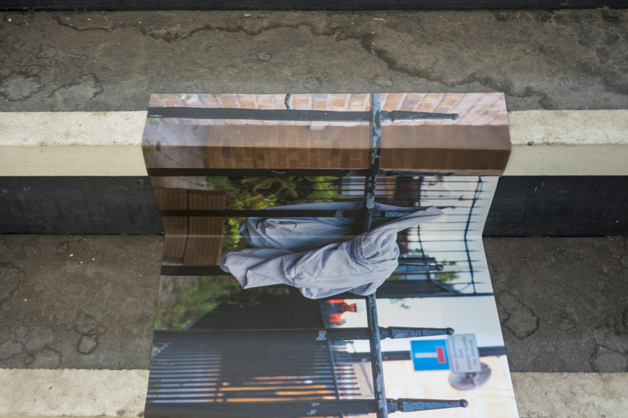 a close-up view of the first colour print on glossy paper of the top of a skyscraper against a grey sky, in the centre of which is a Costa coffee cup